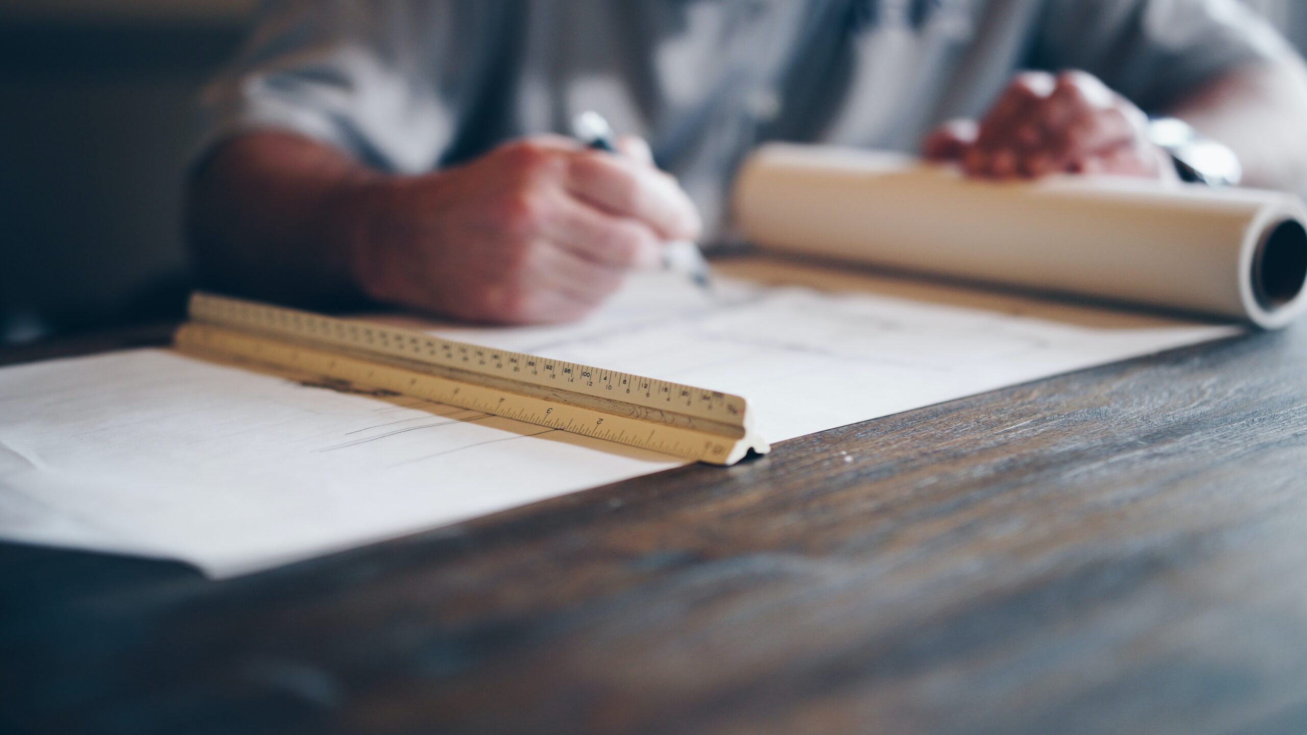 A person working on a set of drawings with a ruler.